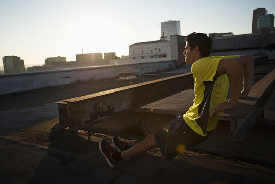 A Man In Exercise Clothes On A Rooftop Overlooking The City, Doing Bench Shoulder Push Ups, 