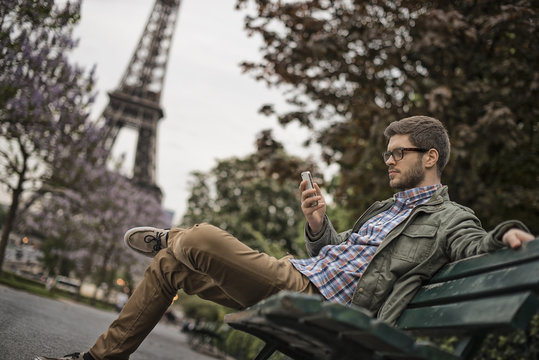 Man sitting on bench in park in Champs de Mars, Eiffel Tower in background