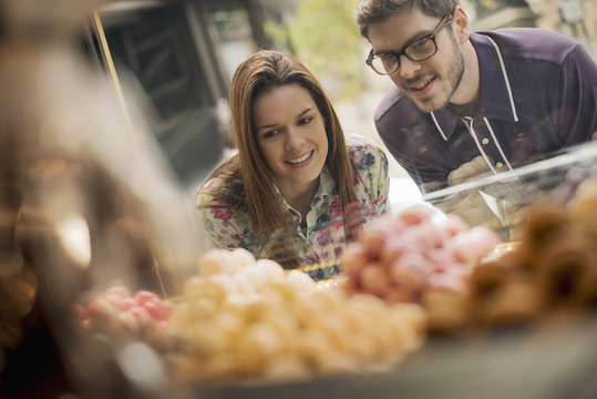 A couple looking at the window display in a confectionery shop,