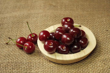 Ripe cherries on a wooden plate.
