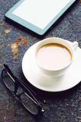 Cup of coffee, tablet computer and  glasses on the background of the iron