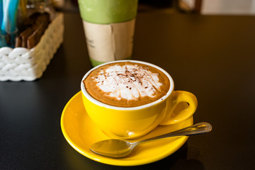 yellow cup of coffee on cafe table