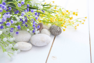 Spa stones with wild flowers on wooden table
