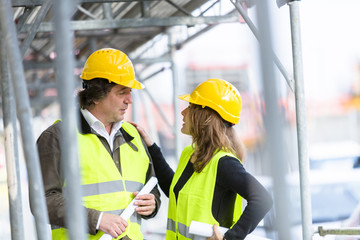 Male and female engineers talking at a construction site