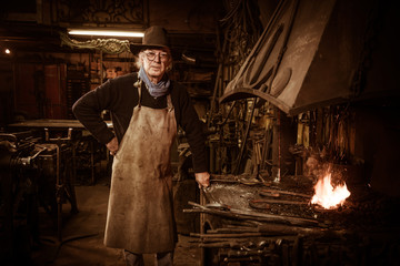 Ironworker forging hot iron in workshop