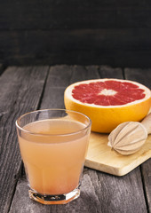Grapefruit juice in glass glass on dark wooden background