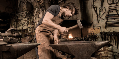 Ironworker forging hot iron in workshop