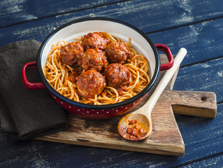 Spaghetti and meatballs in tomato sauce on wooden rustic board. Delicious lunch