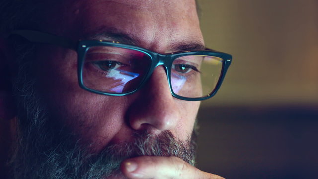 Close up shot of a beard man browsing the internet for information about terrorism, cyber crime hacking at late night.