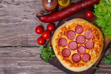 Hot Homemade Pepperoni Pizza on a wooden background with vegetables Ready to Eat