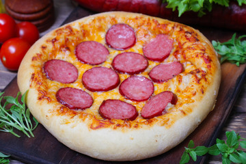 Hot Homemade Pepperoni Pizza on a wooden background with vegetables Ready to Eat