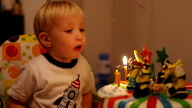 adorable three year old boy celebrating his birthday and blowing candles