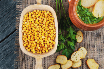 Pea soup in a pot with parsley and croutons, dried peas on a wooden background