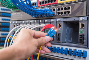 man working in network server room with fiber optic hub for digi