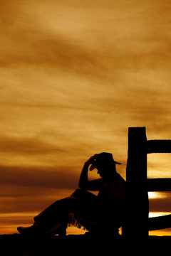 silhouette of cowboy sit by post look down