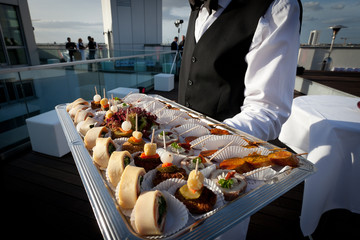 waiter is offering a flying food buffet - obrazy, fototapety, plakaty