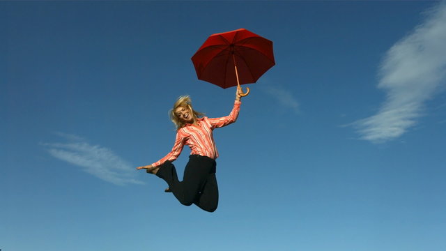 Woman jumping with umbrella in slow motion