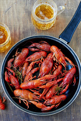 Red boiled crayfish on a pan and a glass of beer.