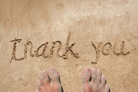 Conceptual thank you text handwritten in sand