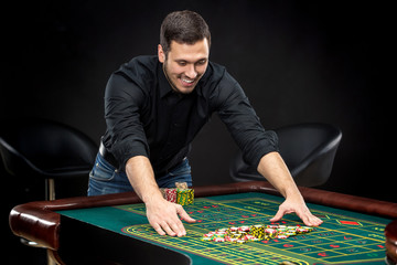 Young handsome man playing roulette wins at the casino