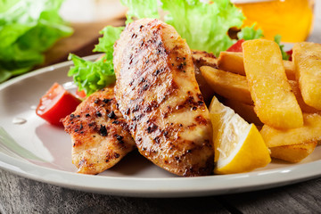Grilled chicken breasts served with fries and fresh salad