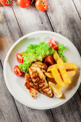 Grilled chicken breasts served with fries and fresh salad