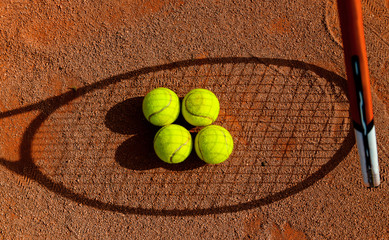 Cztery piłki tenisowe w cieniu rakiety do tenisa ziemnego. - obrazy, fototapety, plakaty