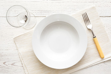 Empty white round soup or pasta plate with fork and glass. On wh