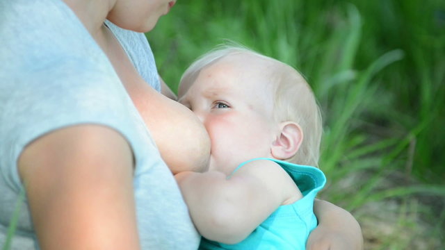 Young mother breastfeeding a baby in nature