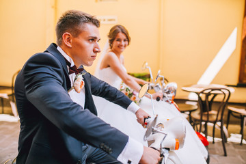 Happy bride and groom hugging, smile and posing near scooter 