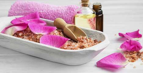 Spa setting with rose bath salt, rose petals and body-care oil b