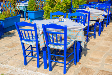 Fototapeta na wymiar Blue chairs with tables in typical Greek restaurant in port of Pythagorion on Samos island, Greece