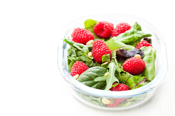 Green  salad with arugula and berries and pine nuts on white