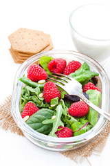 Green  salad with arugula and berries and pine nuts on white tab