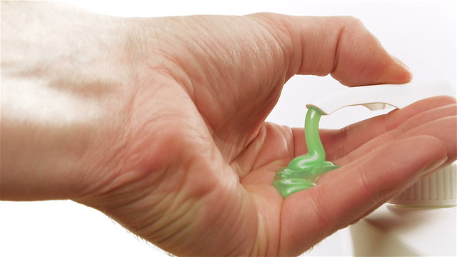 Pumping blue green liquid soap on a hand of a man on white background
