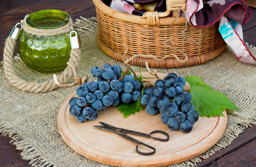 грозди синего винограда с зелеными листьями на деревянной доске
