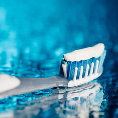 toothbrush on blue background with water drops