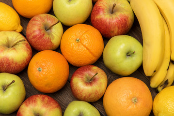 Tasty fruit background with orange, apples and banana on the wooden boards table