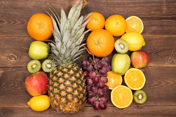 Obraz na płótnie Canvas Tasty fruit background with orange, kiwi, grape, apples and lemon on the wooden table