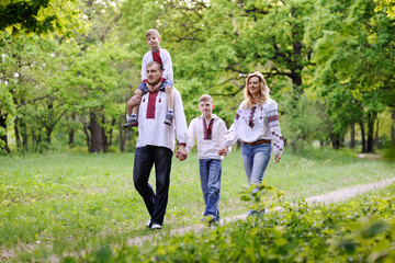 Obraz premium family in Ukrainian embroidered shirts are on a path in a forest