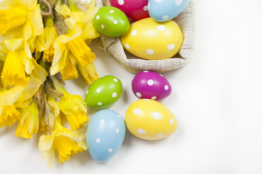 Easter background with colorful Easter eggs and a bouquet of yellow daffodils
