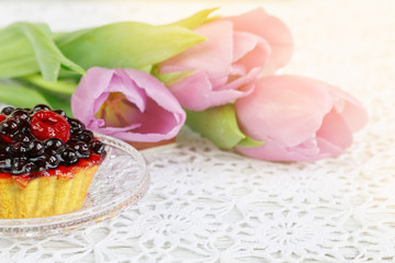 Obraz na płótnie Canvas cup of karkadeh red tea with berries cake and tulips
