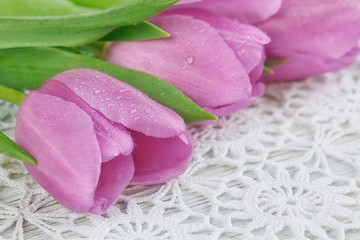 Fototapeta na wymiar Purple tulips on a beautiful crochet tablecloth