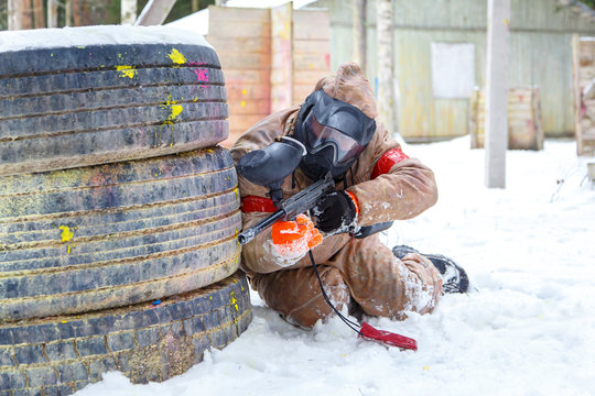 Paintball game in winter. Cool shooter behind fortification.