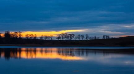 Close up of opposite shore of lake after sunset