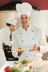 Portrait of a man chef presenting a plate of fine food.