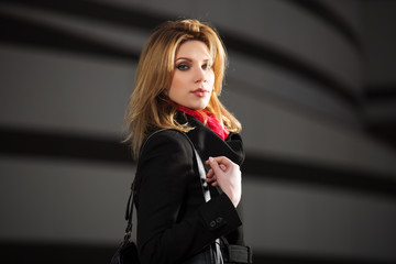 Fashion blond woman in black coat walking on night city street