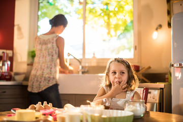 Blonde girl licking chocolate on her fingers in the kitchen.