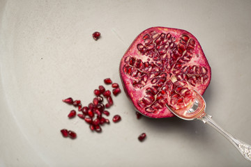 Fototapeta premium Half a Pomegranate with a spoon sticking out, shot on a grey bac