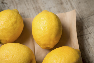 Four lemons on brown paper against a wooden background